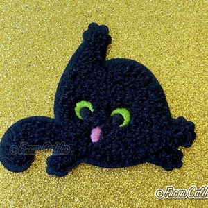 May include: Black cat patch with green eyes and a pink mouth. The cat is embroidered with a textured, curly thread. The patch has a whimsical design, perfect for Halloween or cat lovers. The background is a gold glitter surface.