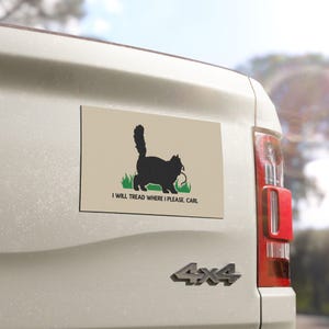 May include: A rectangular beige sticker featuring a black silhouette of a cat standing in green grass. The cat has a fluffy tail and is holding a small object in its mouth. Below the cat, the text reads: I WILL TREAD WHERE I PLEASE. CARL.