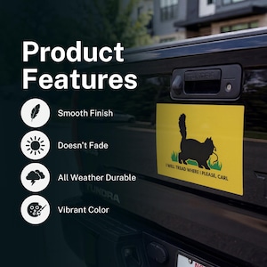 May include: A yellow rectangular sticker featuring a black cat silhouette on a green patch of grass. The text "I WILL TREAD WHERE I PLEASE, CARL" is below the cat. The sticker is on a black vehicle.