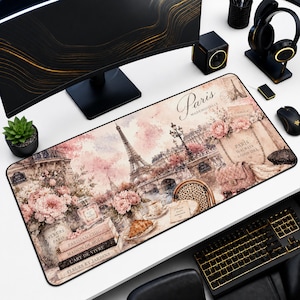 May include: A rectangular desk mat featuring a watercolor-style illustration of Paris with the Eiffel Tower, pink flowers, a croissant, and stacked books labeled Parisian Chic, Maison de Mode, L'Art de Vivre, and Fleurs et Jardins with text.
