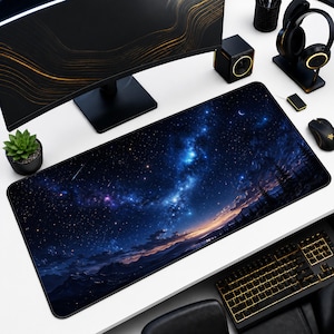 May include: A rectangular mouse pad featuring a vibrant depiction of a starry night sky with a blue and purple nebula, a crescent moon, and silhouetted trees. The pad is surrounded by a black border and is designed for use with a computer mouse.