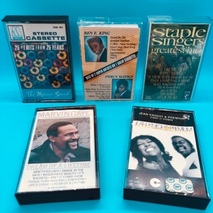 May include: A collection of vintage cassette tapes featuring classic R&B and soul artists. The tapes include albums by Marvin Gaye, Ben E. King, The Staple Singers, and Jean Knight. The cassette cases are clear with colorful album art.