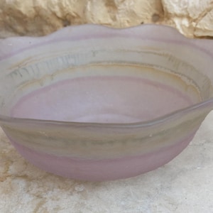 Puede incluir: Un cuenco de vidrio esmerilado con borde festoneado y diseño degradado en rosa y gris.