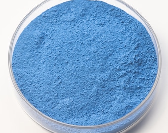 May include: A clear, round petri dish filled with a fine, light blue powder. The powder has a textured surface and fills the dish completely. The dish is set against a plain white background.