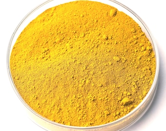 May include: A close-up shot of a clear, round petri dish filled with a vibrant yellow powder. The powder has a fine, granular texture and fills the dish completely. The dish is set against a bright white background, highlighting the color and texture of the powder.