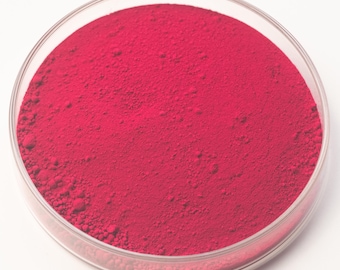 May include: A clear, circular petri dish filled with a vibrant, finely ground red powder. The powder has a slightly textured surface and fills the dish completely, creating a solid, uniform color.