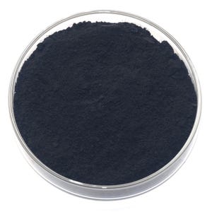Op de afbeelding: Een close-up van een heldere, ronde petrischaal gevuld met een donkerblauw poeder. Het poeder heeft een fijne, korrelige textuur en vult de schaal. De schaal staat tegen een heldere witte achtergrond.