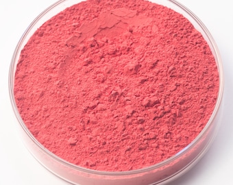 May include: A clear, round petri dish filled with a vibrant, coral-colored powder. The powder has a fine, textured appearance, filling the dish completely. The dish is set against a plain white background.