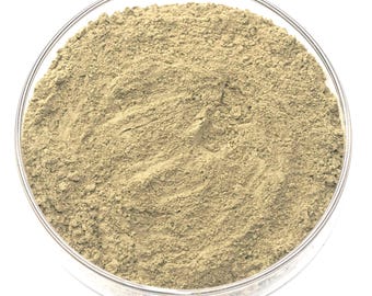 May include: A clear glass bowl filled with a light brown, finely ground powder. The powder has a slightly textured appearance and fills the bowl completely. The bowl is set against a white background.