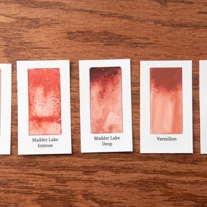 five different shades of red paint, each with a label indicating the name of the color.