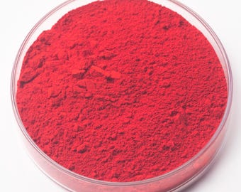 May include: A clear, round petri dish filled with vibrant red powder. The powder has a fine, granular texture and fills the dish completely. The dish is set against a plain white background.