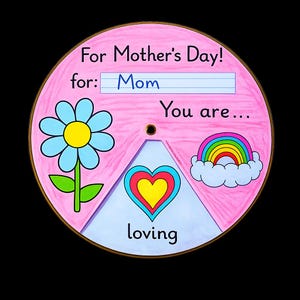 Könnte beinhalten: Eine runde, rosa Muttertagskarte mit Illustrationen einer blauen Blume, eines Regenbogens und eines Herzens. Der Text auf der Karte lautet: "Zum Muttertag! für: Mama Du bist... liebevoll."