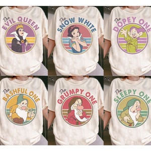 Op de afbeelding: Crèmekleurige T-shirts met Disney-personages: De boze koningin, Sneeuwwitje, Dopey, Bashful, Grumpy en Sleepy. Elk shirt heeft een cirkelvormige afbeelding met de afbeelding en naam van het personage in retrostijl.