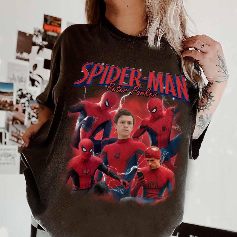 Może przedstawiać: Ciemnoszara koszulka z grafiką Spider-Mana i napisem "Spider-Man Peter Parker" w kolorze czerwonym i niebieskim. Projekt zawiera wiele zdjęć Spider-Mana w pozach akcji, z czerwoną i niebieską kolorystyką.