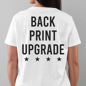 May include: White t-shirt with the words "BACK PRINT UPGRADE" in bold black letters on the back, along with four black stars below the text. The shirt is plain and simple.