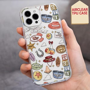 Peut inclure: Une coque de téléphone en TPU transparent avec un motif répétitif d'illustrations colorées incluant une étoile de shérif, un extraterrestre vert, un chapeau rouge, un fer à cheval, des blocs de construction et le texte You've got a friend in me.
