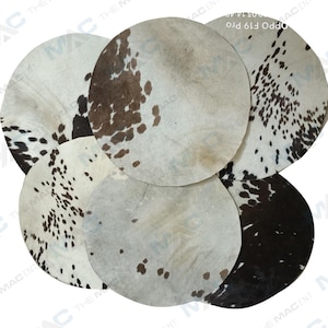May include: Five round cowhide rugs with a white background and black and brown spots. The rugs are arranged in a circle.