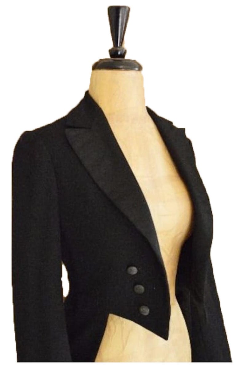 Puede incluir: Chaqueta de esmoquin negra con solapa de muesca y tres botones. La chaqueta se exhibe en un maniqu&iacute;. La chaqueta a medida tiene un dise&ntilde;o cl&aacute;sico, adecuado para eventos formales. La tela de la chaqueta parece ser un material liso y oscuro.