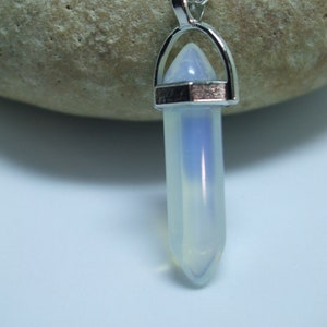 May include: A silver chain necklace with a clear, iridescent crystal pendant in the shape of a point. The pendant is set in a silver frame.