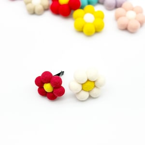 May include: A set of felt flower car air fresheners in various colors, including red, white, yellow, pink, and blue. The flowers have a simple design with a yellow center and are attached to a black clip.