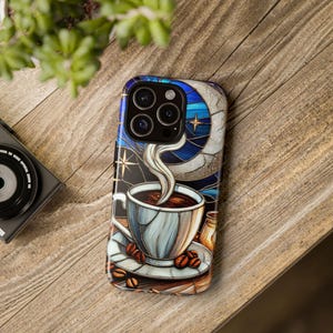 Peut inclure: Une coque de téléphone avec un motif de vitrail représentant une tasse de café avec de la vapeur qui s'en échappe, une lune croissante et des étoiles. La coque est conçue pour un téléphone avec un triple objectif d'appareil photo.