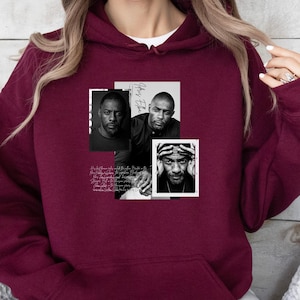 May include: Burgundy hoodie with a front graphic featuring three black and white portraits of a man. The graphic includes the name "Idris Elba" and other text. The hoodie has a front pocket and a drawstring hood.