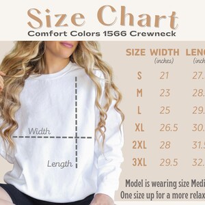 May include: A white Comfort Colors 1566 Crewneck sweatshirt with a size chart. The chart displays measurements in inches for sizes S to 3XL, including width and length. The text also mentions the model is wearing a Medium size.
