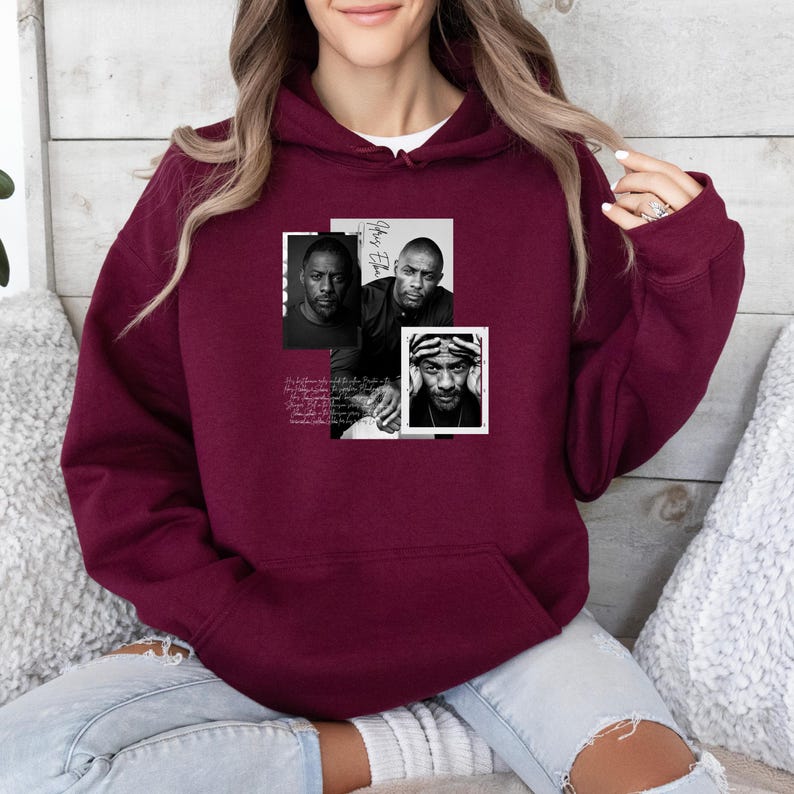 May include: Burgundy hoodie with a front graphic featuring three black and white portraits of a man. The graphic includes the name "Idris Elba" and other text. The hoodie has a front pocket and a drawstring hood.