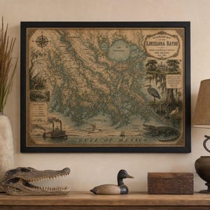 May include: Framed vintage map of the Louisiana Bayou, featuring detailed illustrations of the Mississippi River, wildlife, and a steamboat. The map is in a black frame and includes the text "Illustrated Map of the Louisiana Bayou".