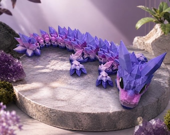 May include: A multi-jointed, articulated dragon figurine featuring a gradient color scheme of purple, pink, and blue. The creature is covered in sharp, geometric, crystal-like spikes along its back, tail, and head, with large black eyes.