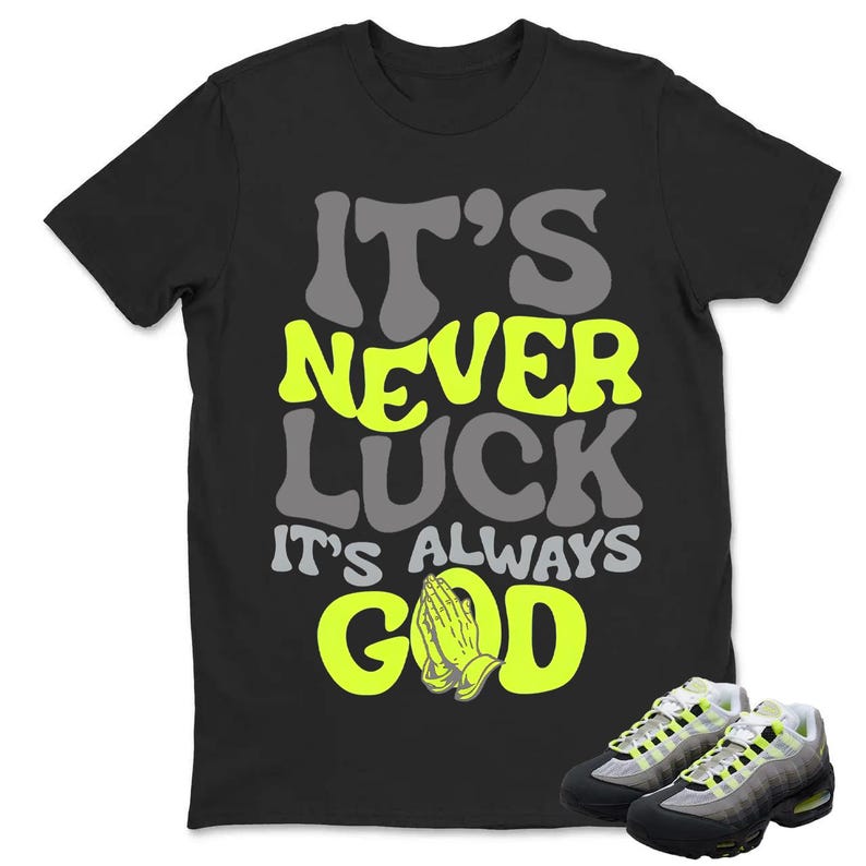 Puede incluir: Camiseta negra con el texto "IT'S NEVER LUCK IT'S ALWAYS GOD" en gris y amarillo ne&oacute;n. La imagen tambi&eacute;n muestra un par de zapatillas grises, negras y amarillo ne&oacute;n.