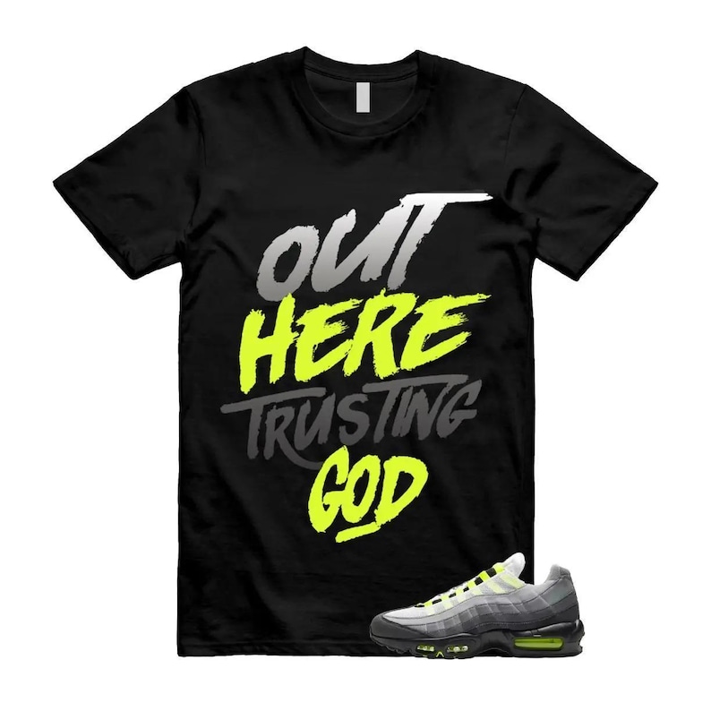 May include: Black t-shirt with the text "OUT HERE TRUSTING GOD" in white, yellow, and grey. A pair of grey, black, and yellow athletic shoes are in the lower right corner.