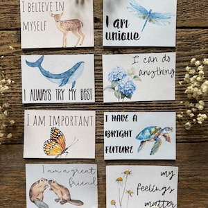 May include: A collection of eight rectangular cards with inspirational messages and watercolor illustrations. The cards feature images of a deer, dragonfly, whale, flowers, butterfly, turtle, beavers, and daisies. Each card has a unique message in black script.