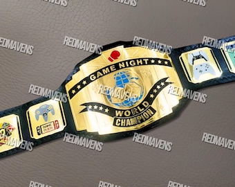 May include: A gold-colored "Game Night World Champion" belt with a blue leather strap. The belt features a central emblem with a globe and dice, and smaller emblems with game controller graphics. The text "GAME NIGHT" and "WORLD CHAMPION" are visible.