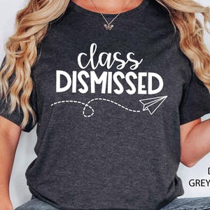 May include: Dark grey heather t-shirt with the words "class DISMISSED" in white script and a paper airplane graphic. The shirt is a crew neck style.