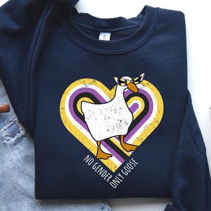 May include: Navy blue sweatshirt featuring a white goose wearing sunglasses, set against a heart-shaped design with yellow, purple, and black stripes. The text "NO GENDER ONLY GOOSE" is printed around the heart.