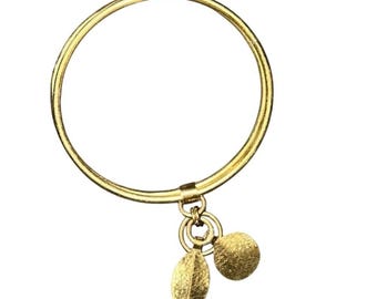 Pulseira rígida de latão com pingentes de folha e círculo texturizado, estilo boho.