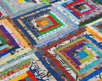 May include: A colorful quilt made of squares within squares, with a variety of fabrics and patterns. The quilt is made in a log cabin style, with each square being a different color and pattern. The quilt is a beautiful example of patchwork quilting.