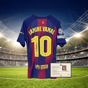 Puede incluir: Una camiseta de fútbol azul y granate con el nombre "LAMINE YAMAL" y el número "10" en amarillo. La camiseta tiene una firma y el logotipo de ACNUR. Se muestra un certificado enmarcado debajo.