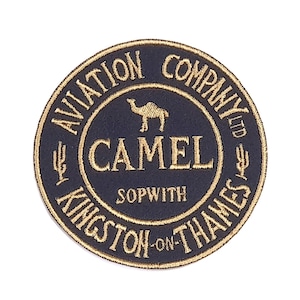 Puede incluir: Un parche bordado en negro y dorado con el texto "Aviation Company Ltd Camel Sopwith Kingston-on-Thames" y una silueta de camello.