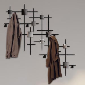 May include: A black metal wall-mounted coat rack with a grid design and small mirrors. Two brown coats are hanging on the rack. A light wood bench with a blue cushion is in front of the rack.