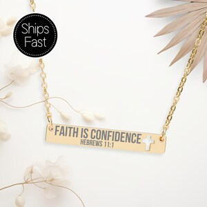 May include: A gold-colored necklace with a rectangular pendant. The pendant has the inscription "FAITH IS CONFIDENCE HEBREWS 11:1" in gray lettering, with a small cross cutout. The necklace is on a white background with floral accents.