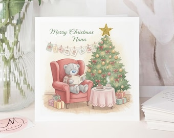 May include: A Christmas card with a watercolor illustration. A teddy bear reads in a red armchair near a decorated Christmas tree. The card reads "Merry Christmas Nana" in green script.