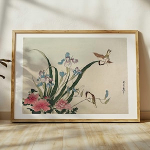 May include: A framed print of a Japanese woodblock print featuring a delicate arrangement of blue and white irises and pink flowers with two small birds perched on a branch. The print is set against a light beige background.