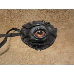 May include: A handcrafted black leather eye patch featuring a large, detailed eye with brown and orange iris. The eye patch has a textured surface and a strap for securing it. The design is unique and artistic.