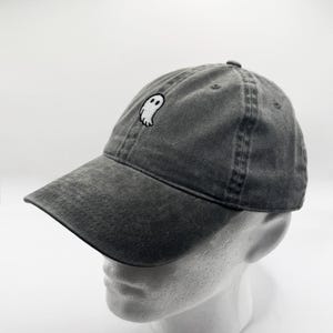 May include: A dark gray baseball cap with a white ghost embroidered on the front.