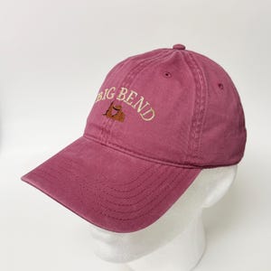 Op de afbeelding: Een kastanjebruine honkbalpet met de geborduurde tekst BIG BEND in een gebogen beige lettertype boven een kleine bruine berggrafiek. De pet heeft een gestructureerde kroon, een gebogen klep met stiksels en ventilatiegaatjes.