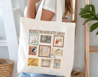 May include: Off-white tote bag displaying vintage postage stamp designs with floral and bird illustrations. The text "RESPECT MASSACHUSETTS LOCALS" is printed at the top. The bag has two handles and is held by a person.