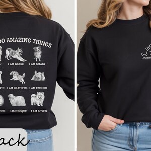 May include: Black sweatshirt featuring the text "I CAN DO AMAZING THINGS" and dog illustrations. The back of the sweatshirt has various dog breeds with positive affirmations. A smaller version of the design is on the front.