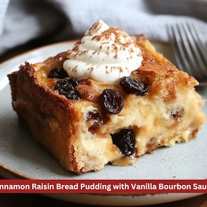 May include: A slice of cinnamon raisin bread pudding topped with whipped cream and sprinkled with cinnamon. The pudding is on a light blue plate.